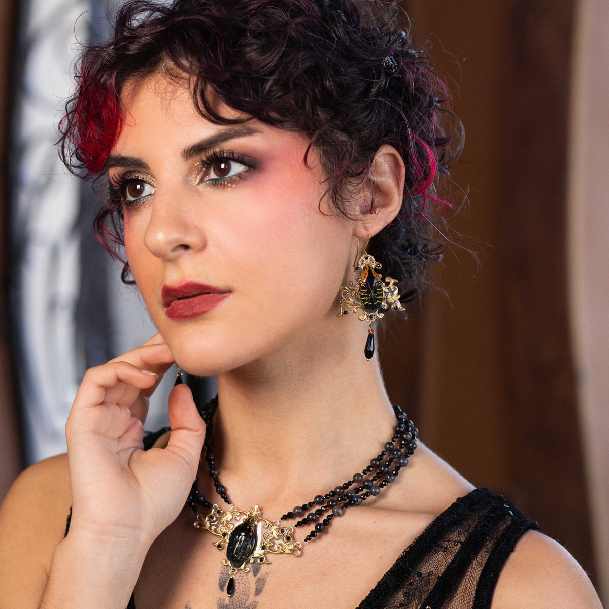 Boucles d'oreille Westwood portées de près – scarabée noir, vert et orange sur laiton doré | Victorian Rehab