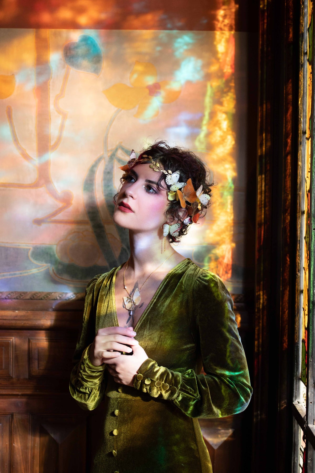Couronne de papillons blancs et orangés portée, devant des vitraux Art nouveau