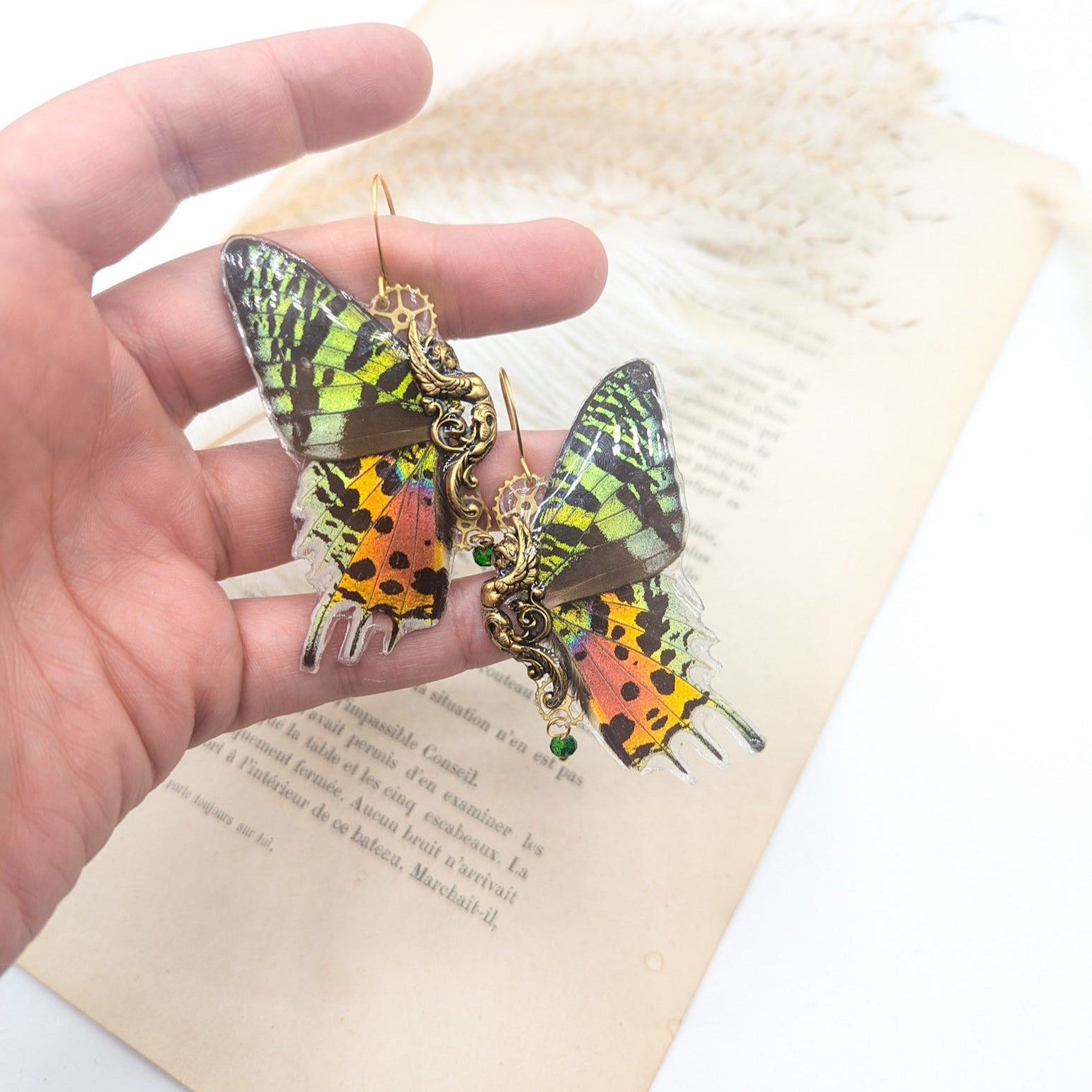 Détail boucles Sphynx Sunset Moth – reflets verts iridescents et orange flamme, laiton doré