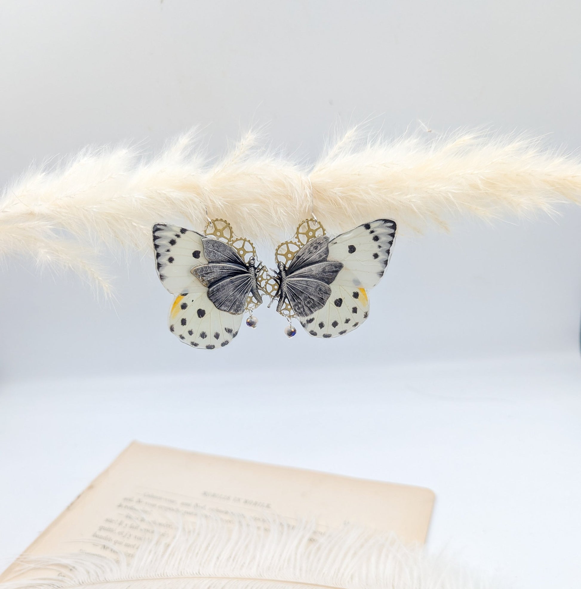 Détail boucles Chrysalide argentées – aile papillon blanc et noir engrenages montre ancienne